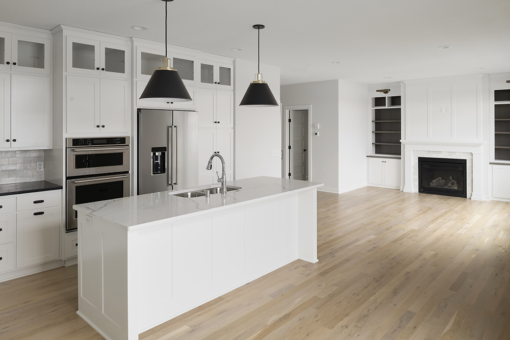 White kitchen with black pendant lights, center island, and built-in fireplace nook