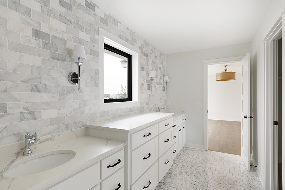 Bathroom with marble subway tile, double vanity, and window
