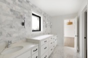 Bathroom with marble subway tile, double vanity, and window